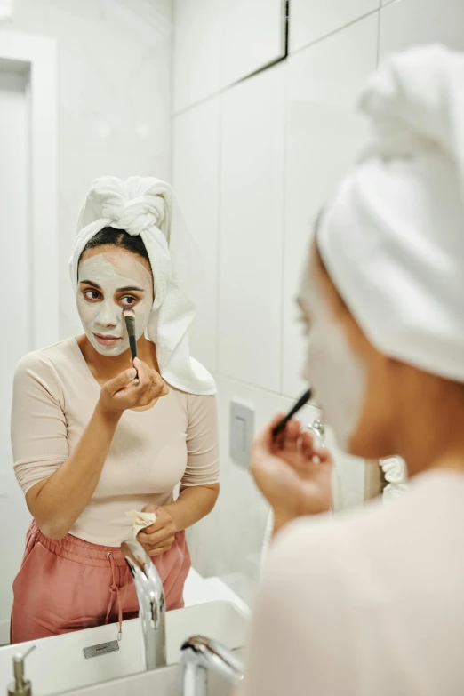 the woman is putting facial care on her face