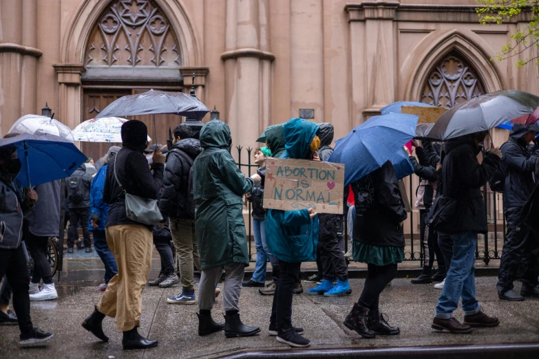 group of people standing in front of a building on a rainy day