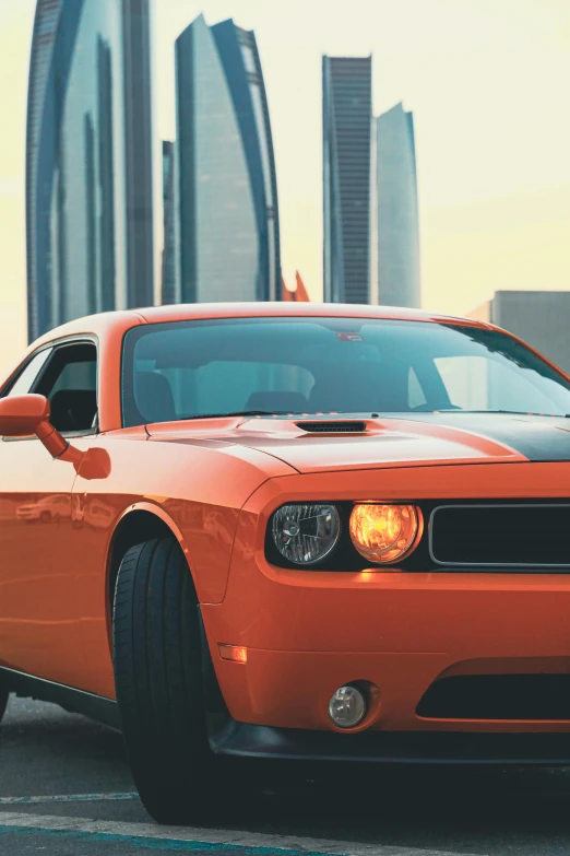 an orange car sits parked in front of a city