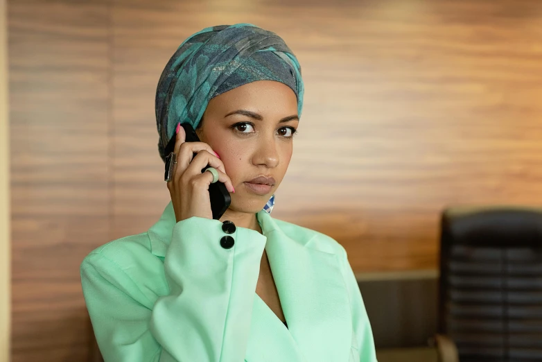 a young woman wearing a headscarf talking on a phone