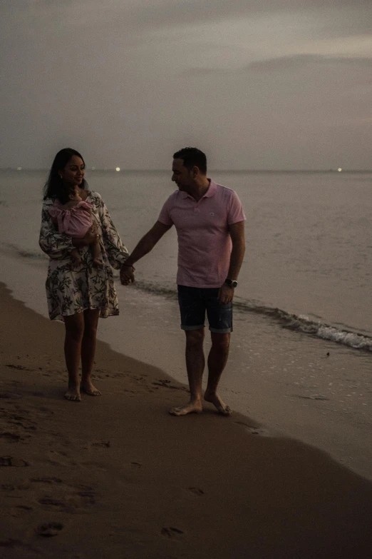 couple holding hands standing on a beach by the ocean