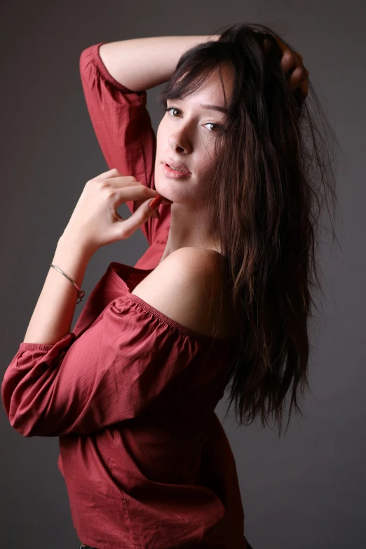 a woman in a red blouse holding her hair back
