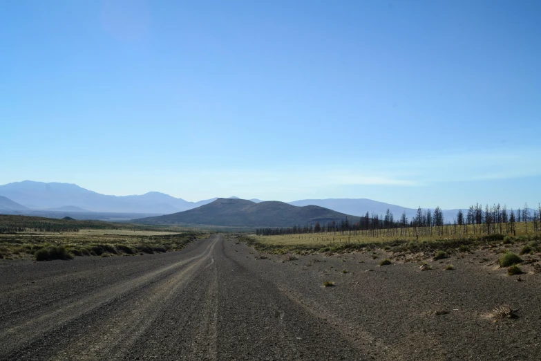 a dirt road that is leading to some mountains