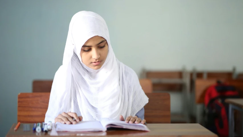 a woman reading in her classroom at her desk