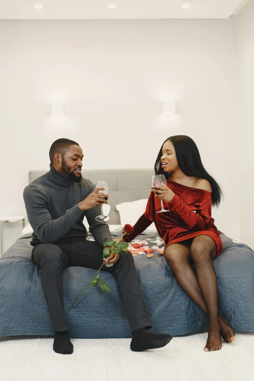 two people sitting on top of a bed next to each other