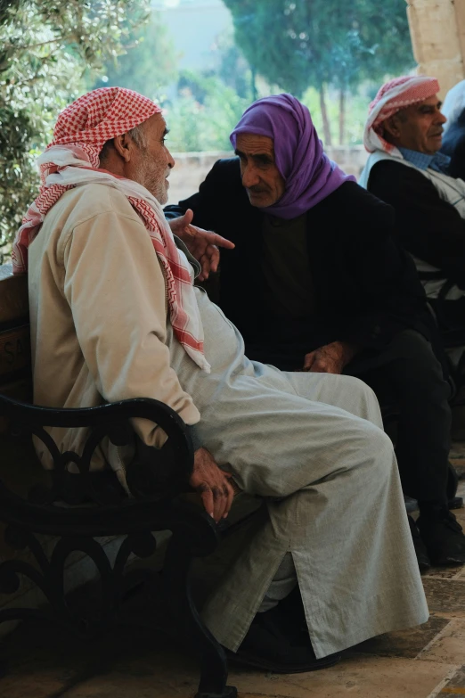 several men and women are sitting on an outdoor bench