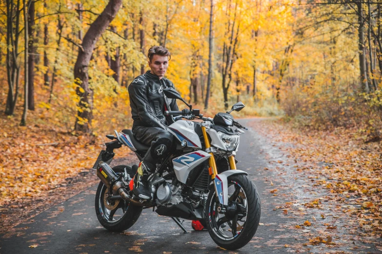 man in leathers riding a motorcycle on a wooded road