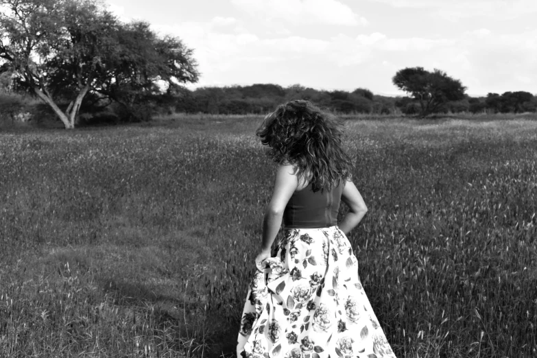 a woman stands in a field of flowers