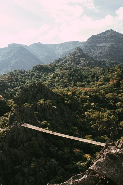 a long suspension bridge above some mountains on a cloudy day