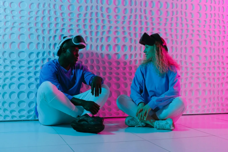 two people sitting against a wall on their knees