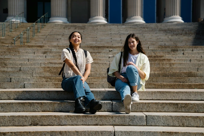 two people sitting on some stairs with their backpacks