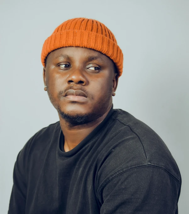 a man wearing a hat and shirt sits for a po