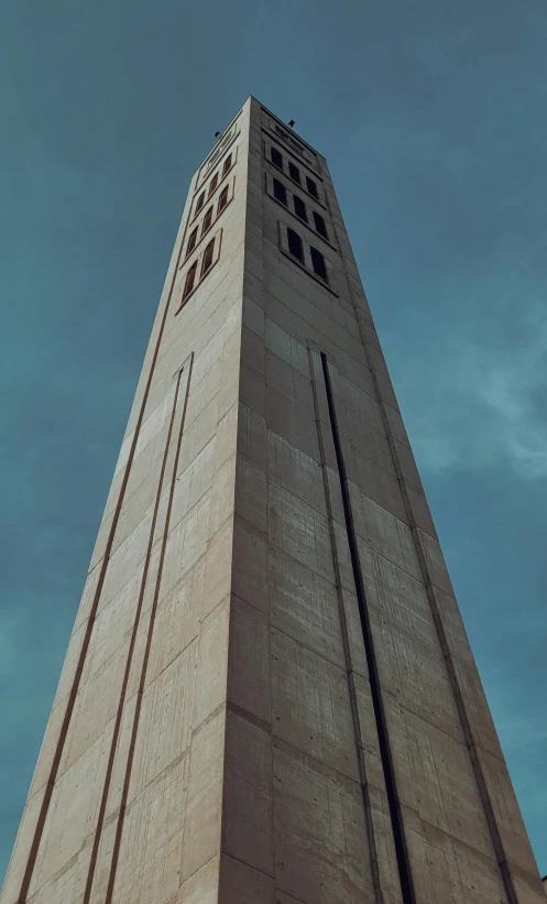 a tall grey tower with many windows against a blue sky