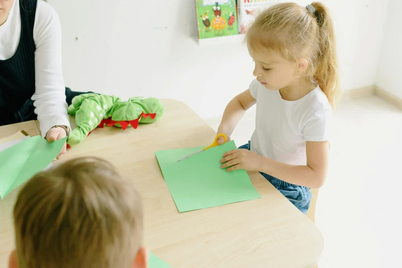 a small girl sitting at a table doing some construction work