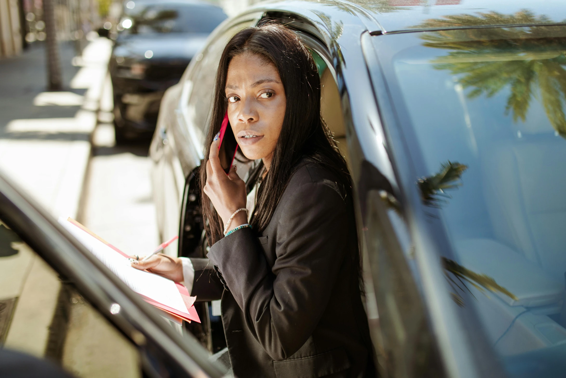 a woman in business attire using a cell phone next to her car