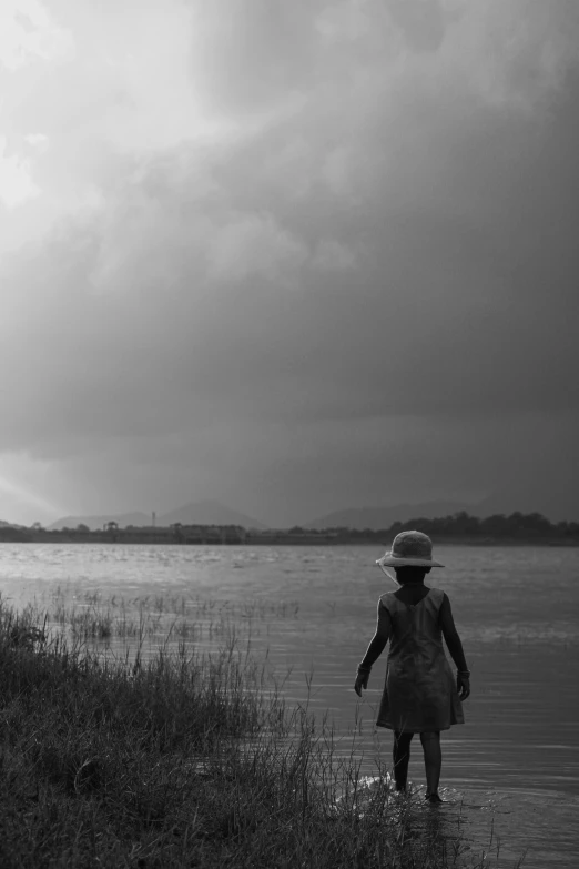 a woman is walking down the shore of a lake