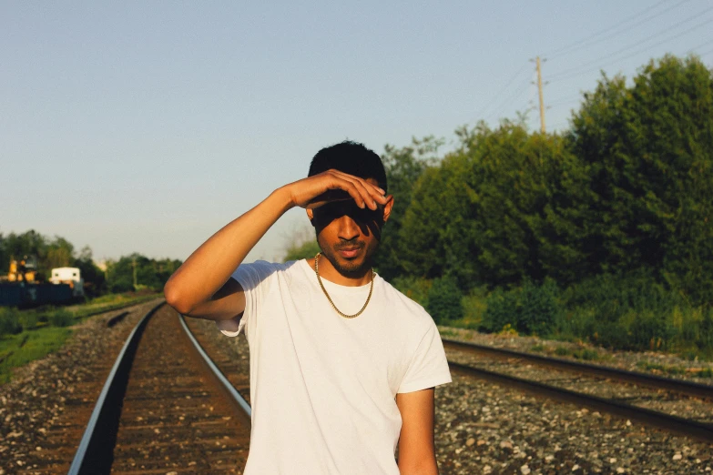 a man poses while on the railroad tracks