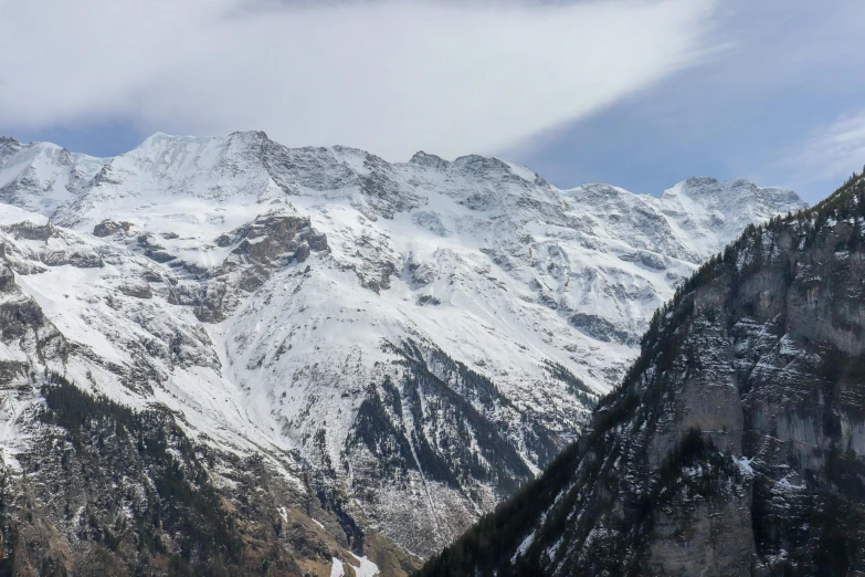 snow covered mountains on a clear day with a small white cloud