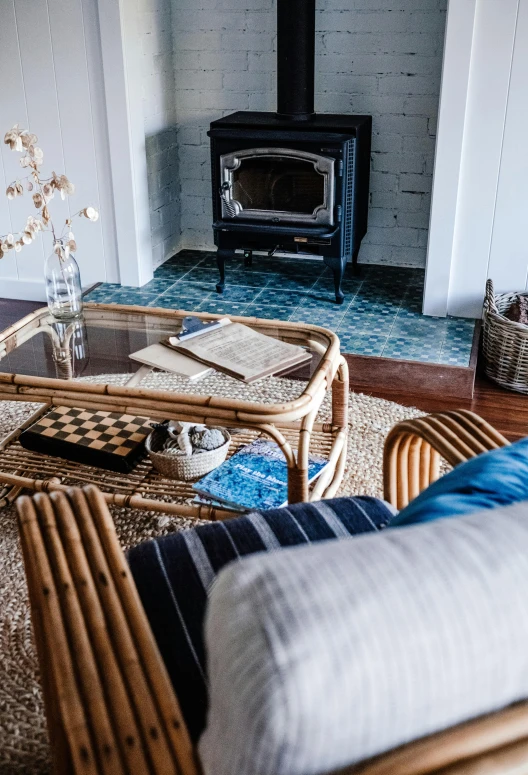 two wicker chairs and a table in front of a fireplace