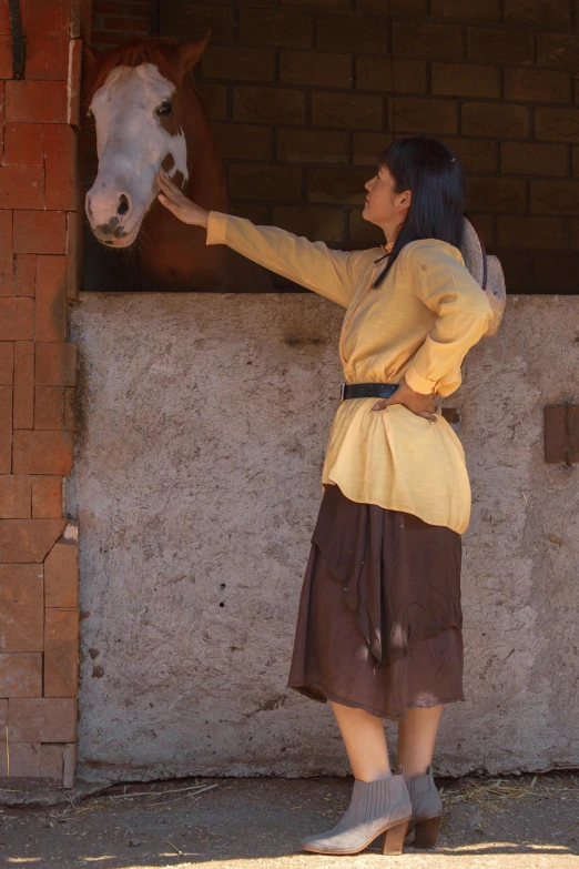 a woman that is petting a horse in the dirt