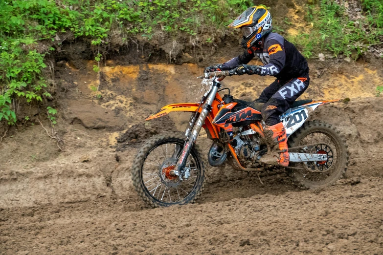 a motor bike rider riding on a muddy track