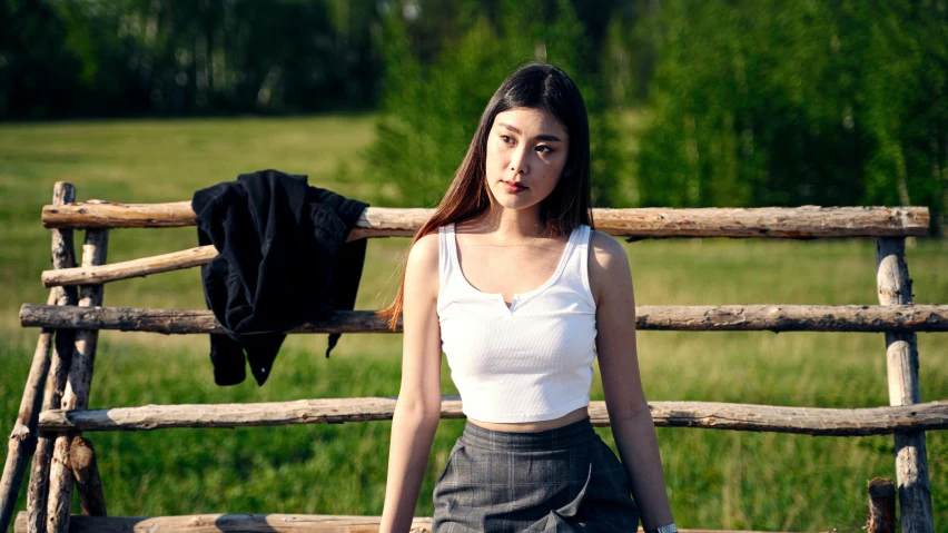 a woman standing near a fence in front of a grassy field