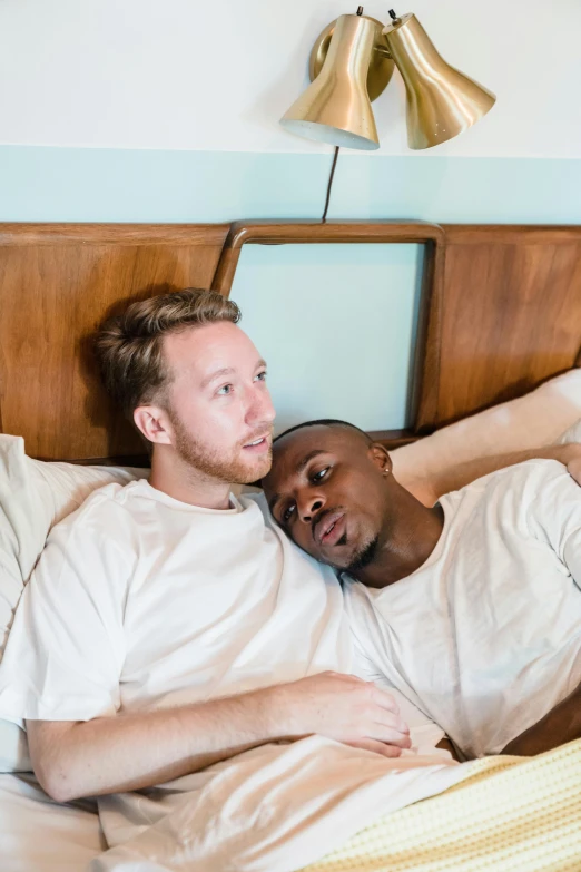 two men are lying in bed together in the bedroom