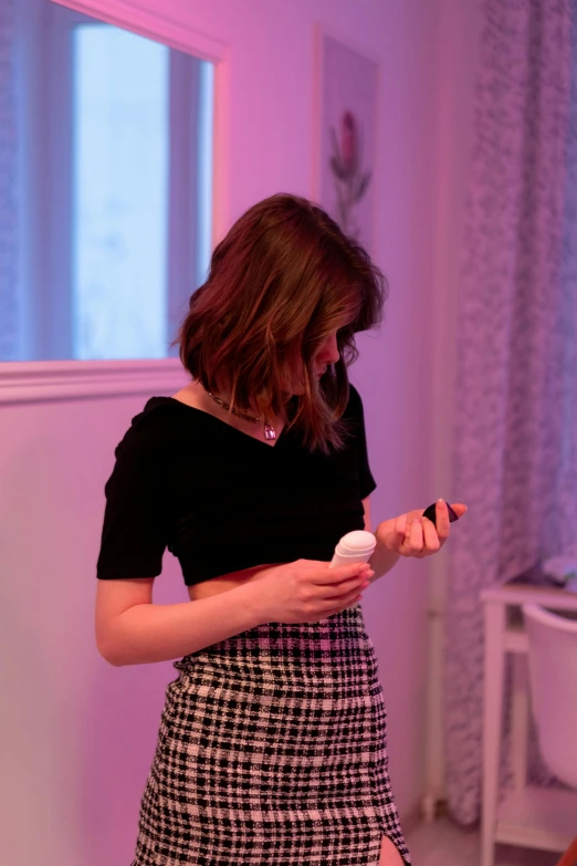 a girl is standing in front of the tv holding the remote