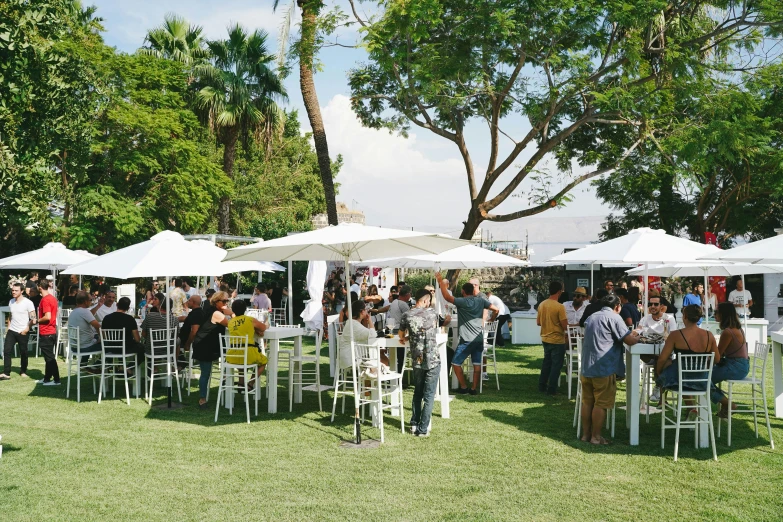 large group of people sitting in white chairs under umbrellas