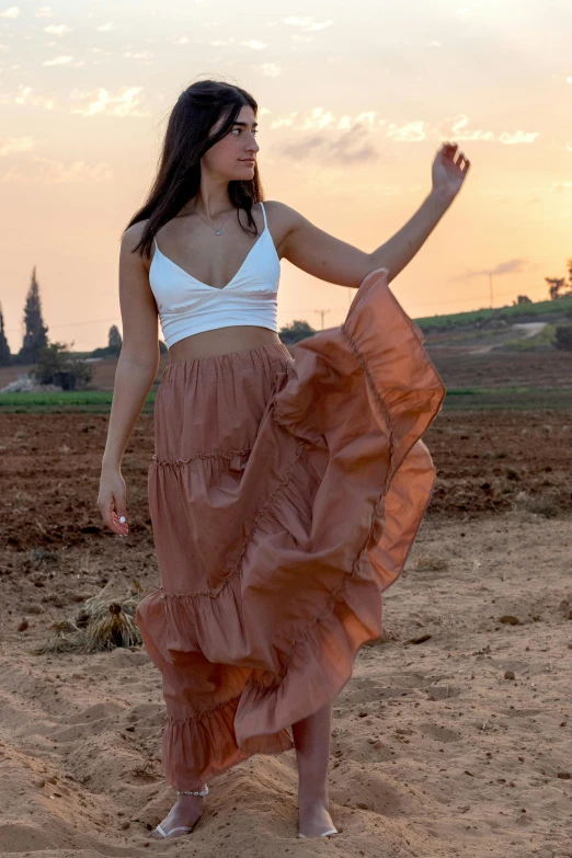 a woman is standing in the dirt wearing a large skirt