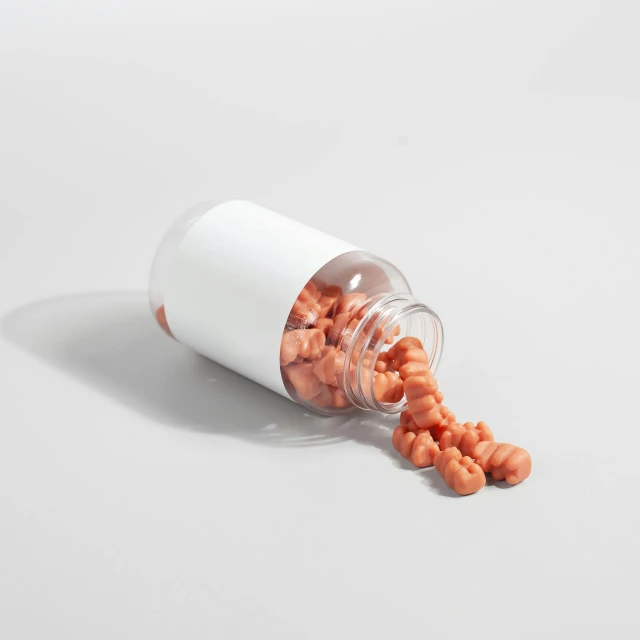 an open pill bottle filled with vitamins on top of a white surface