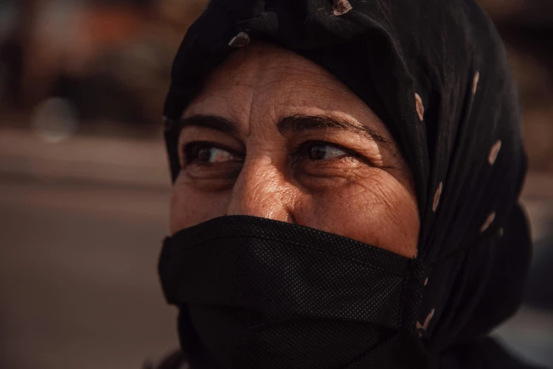 an elderly woman wearing a black bandana looking intently