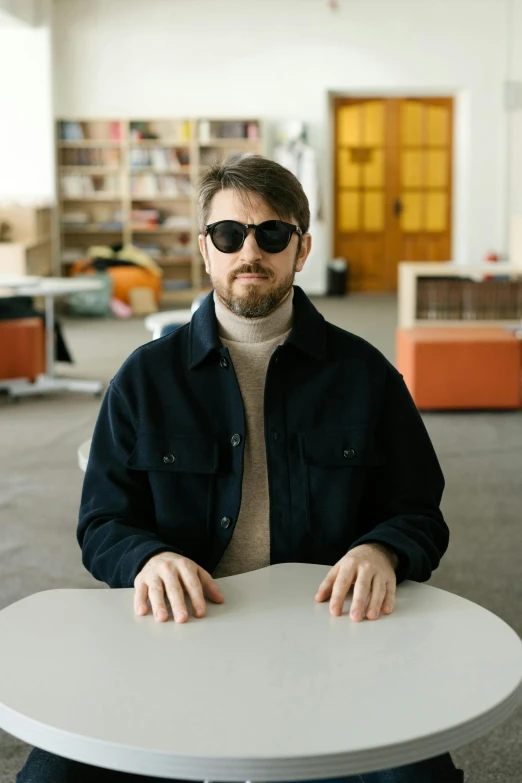 a man wearing shades and standing at a white table