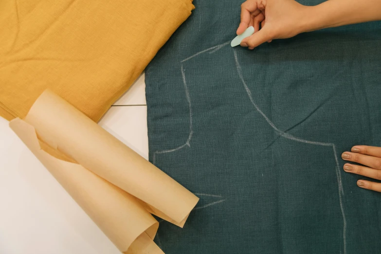 someone uses a needle to stitch the fabric on top of a rug