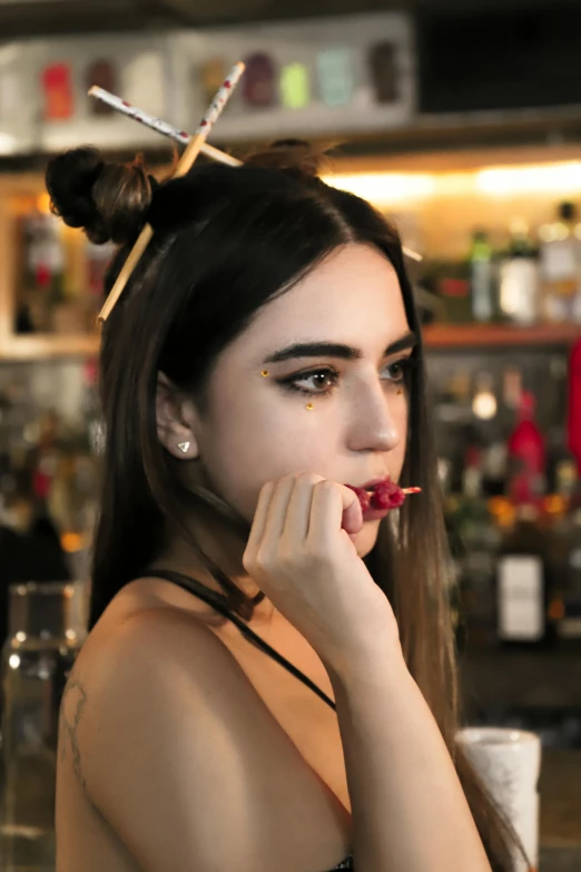 a young woman with black hair putting some food on her nose