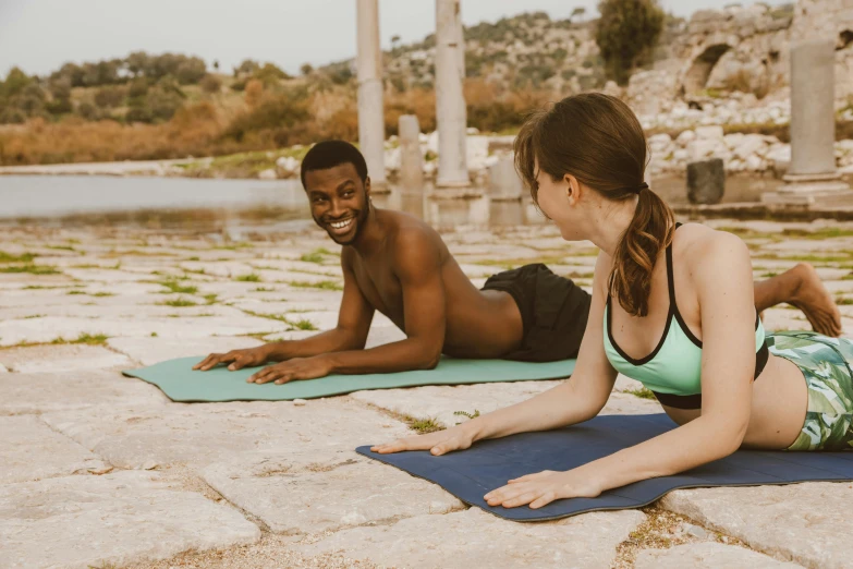 a young woman and man sit on the ground doing yoga