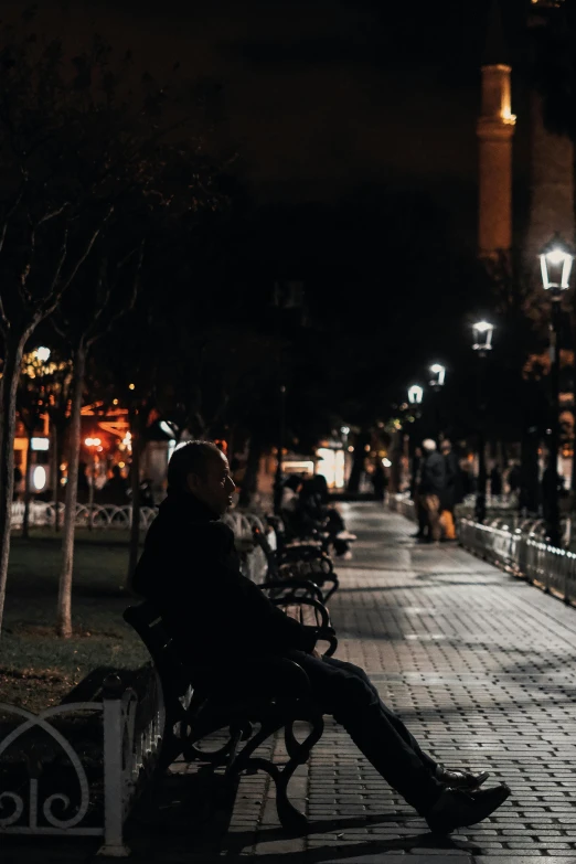 a man sitting alone on a park bench looking at the sky