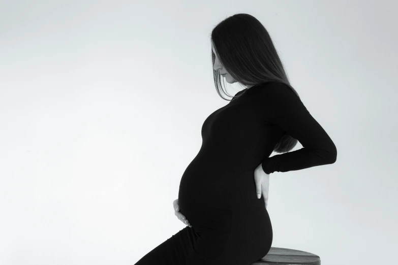 a woman with her hand on her hips while sitting on a chair