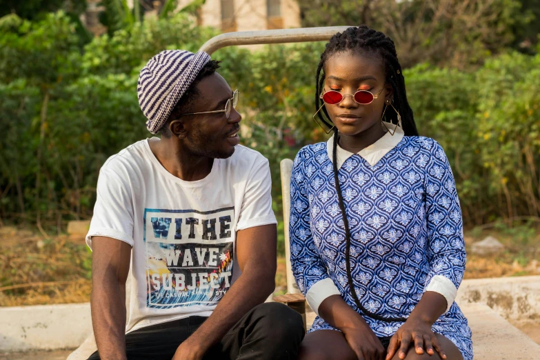 two young people with red sunglasses are sitting on cement