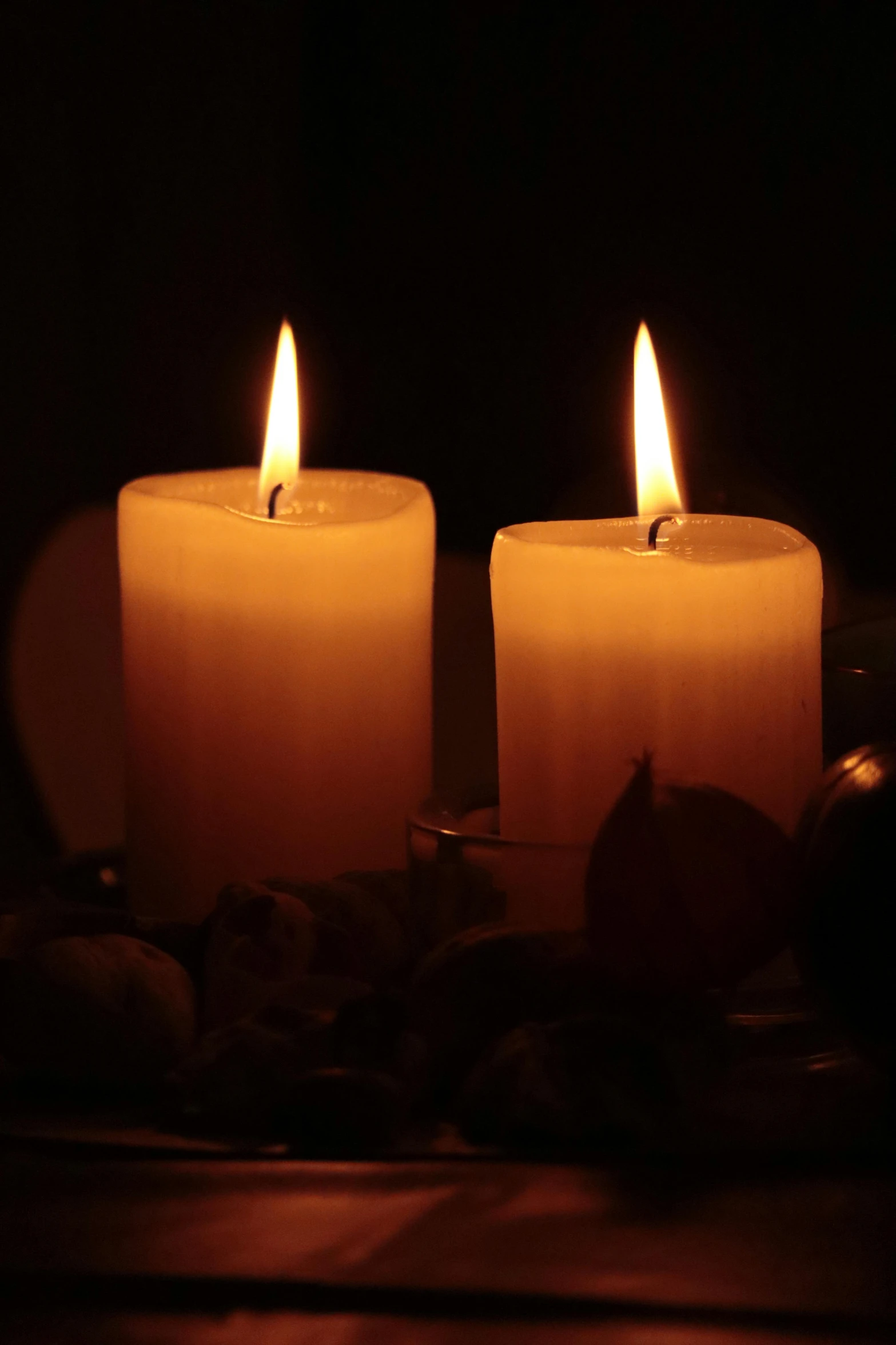 two lit candles sitting on top of a table