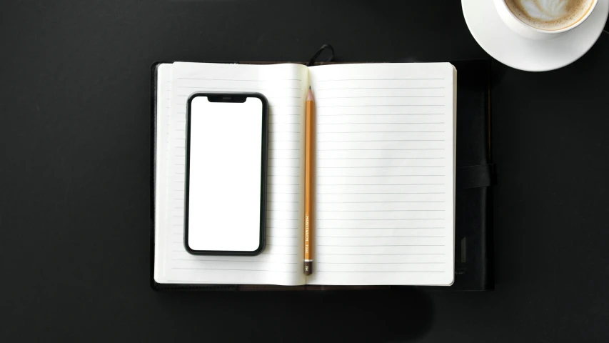 a notepad, pen and phone on a table