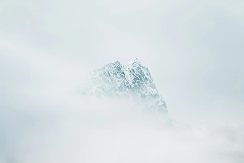 an airplane flying over the mountains in the fog