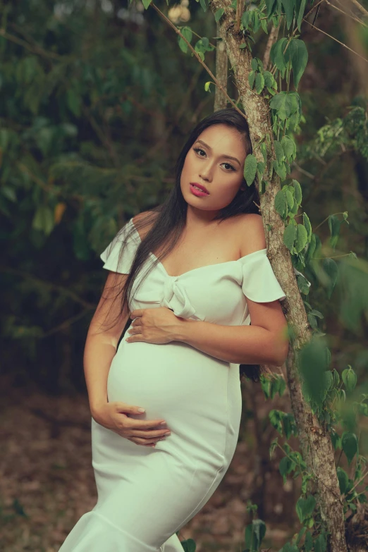 the pregnant woman is wearing a white gown