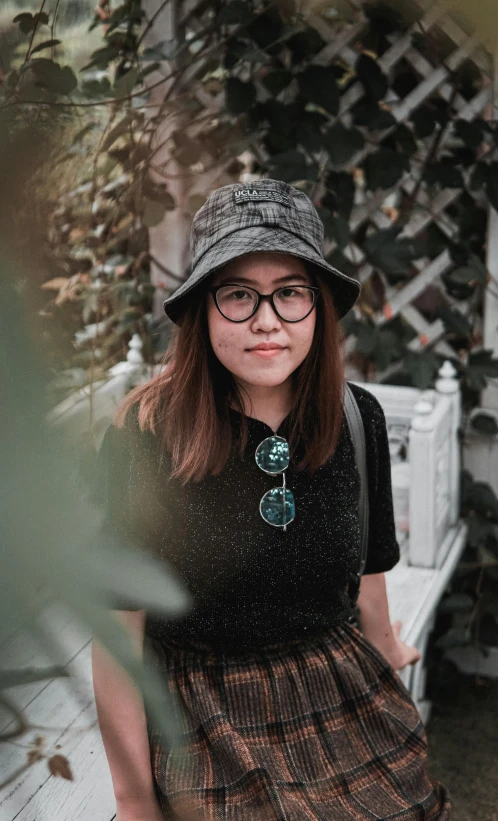  in glasses and hat sits on bench outdoors