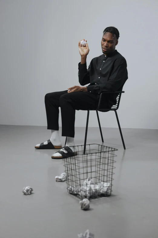 a man sitting on top of a chair in front of a ball filled basket