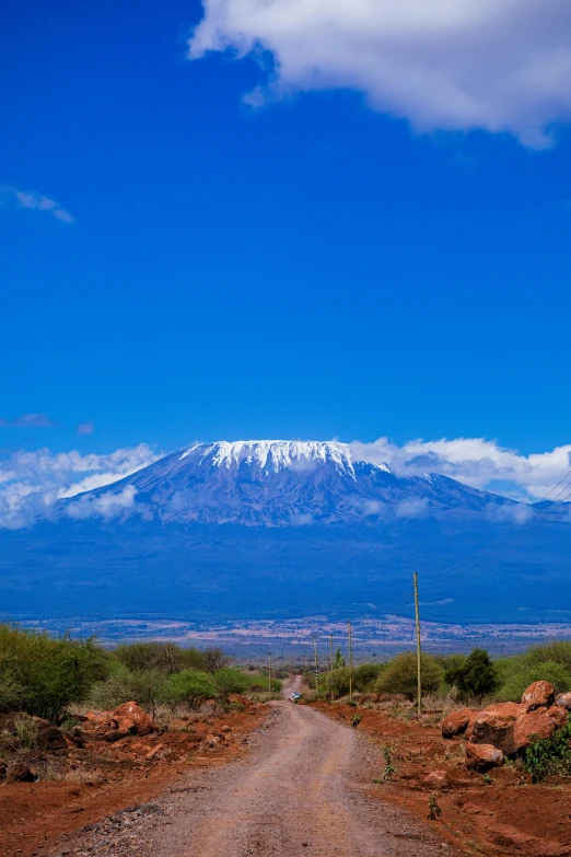 an open dirt road with a mountain in the distance