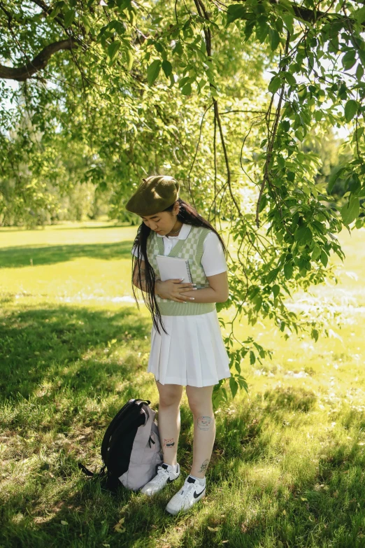 woman with book bag leaning up against tree nch