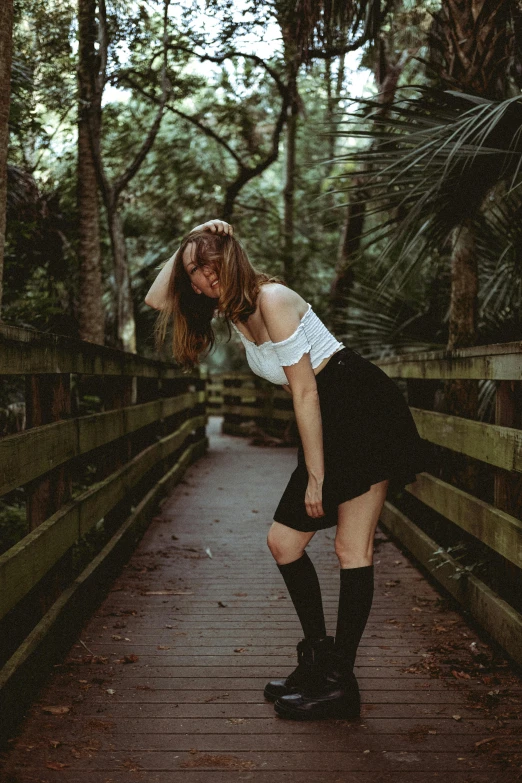 woman bending down wearing knee high boots on a bridge