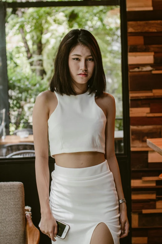 a woman posing in front of a window wearing a white skirt