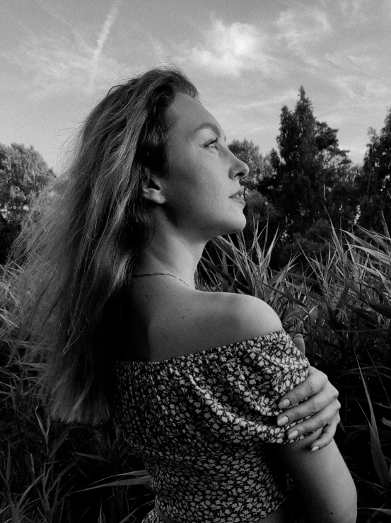 a woman standing in tall grass with her hands together